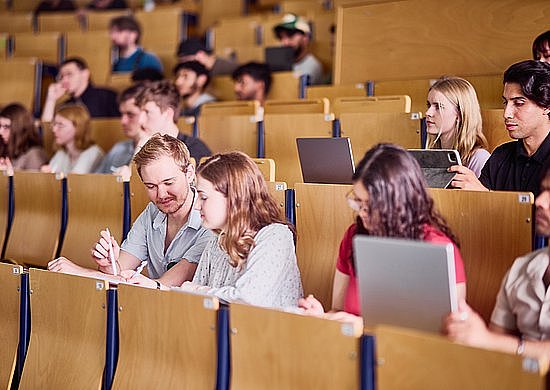 Studierende sitzen in mehreren Reihen in einem hellen Hörsaal